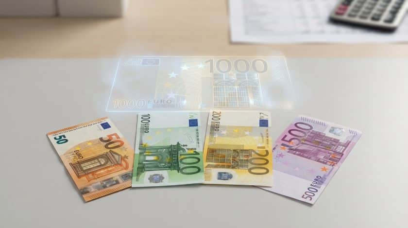 Real 50, 100, 200, 500 Euro banknotes fanned on a grey surface, with a ghostly, translucent 1000 Euro outline above.