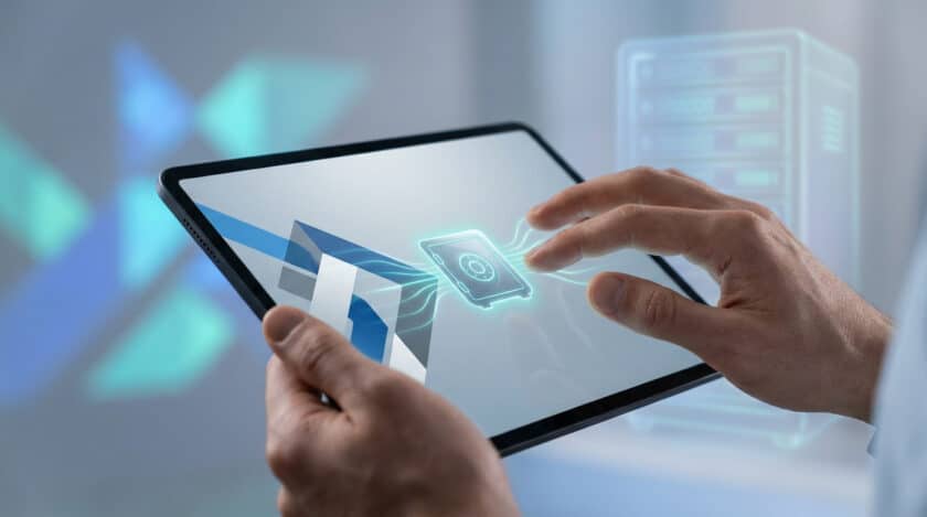 Mains tenant une tablette affichant un coffre-fort numérique lumineux, suggérant un accès sécurisé à des données en ligne.
